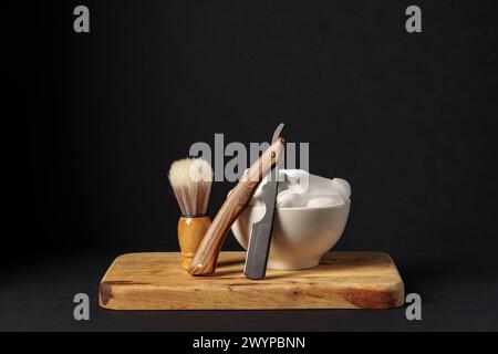 Apparecchiatura di rasatura classica con rasoio, spazzola e sapone su supporto in legno su sfondo scuro Foto Stock