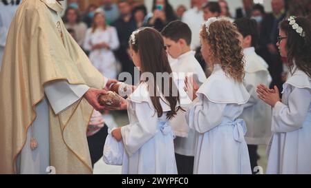 Lida, Bielorussia - 31 maggio 2022: I bambini ricevono il pane dal sacerdote nella Chiesa cattolica. Foto Stock