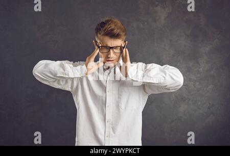 Il lavoratore stanco soffre di gravi mal di testa causati dallo stress e dal burnout emotivo. Foto Stock