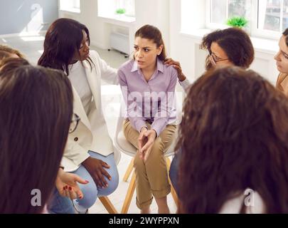 Donne diverse che sostengono una ragazza triste durante una sessione di terapia di gruppo Foto Stock