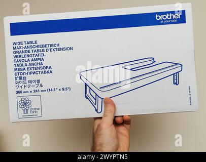 Parigi, Francia - 9 marzo 2024: Mano che regge una scatola di Brother, ampio tavolo per macchine da cucire con descrizione multilingue e illustrazione del prodotto Foto Stock