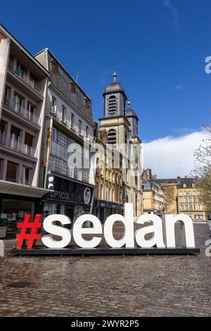 SEDAN, FRANCIA, 4 APRILE 2024: Vista sulla strada della città di Sedan con il cartello "Sedan" in grandi lettere bianche. Sedan è una popolare destinazione turistica in Th Foto Stock