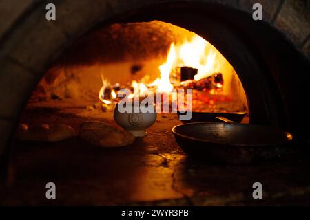 recipiente in ceramica e padelle in forno a mattoni con fiamme Foto Stock