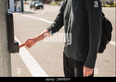 Primo piano di una persona che preme il pulsante della pedana laterale al semaforo Foto Stock