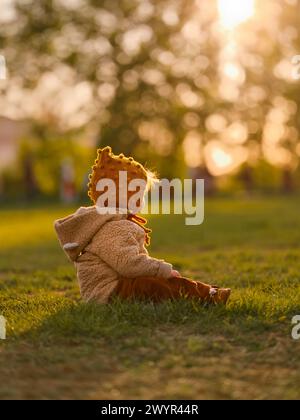 Una bambina di tre anni è seduta sull'erba nel parco centrale. Foto Stock