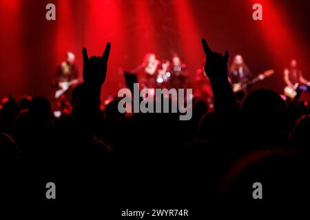 Una dinamica scena di concerti rock con le mani sagomate alzate in alto Foto Stock