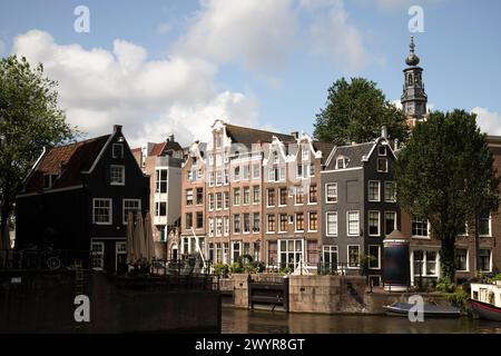 Le strette case del canale di Amsterdam con la chiusa di Sint Antoniesluis sulle Oudeschans con la torre della chiesa dello Zuiderkerk sullo sfondo. Foto Stock