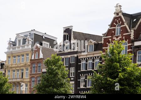 Le facciate storiche delle case sul canale lungo il fiume Amstel ad Amsterdam. Foto Stock