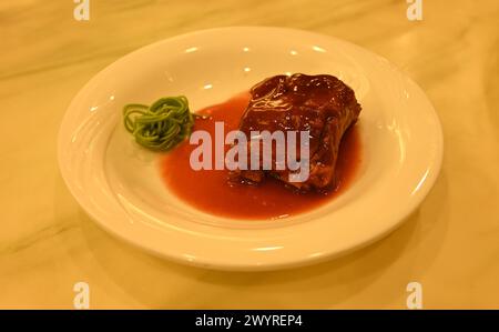 bistecca di maiale brasata fresca con spaghetti verdi in piatto bianco per mangiare Foto Stock