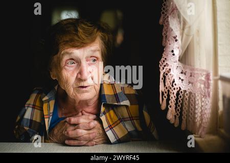 Ritratto di una donna anziana seduta a un tavolo. Foto Stock