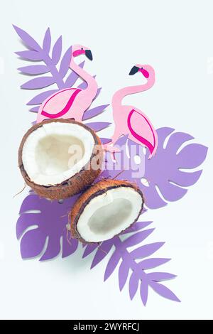 Cocco rotto, foglie tropicali di carta e fenicotteri su sfondo bianco. Sfondo estivo, piatto. Foto Stock