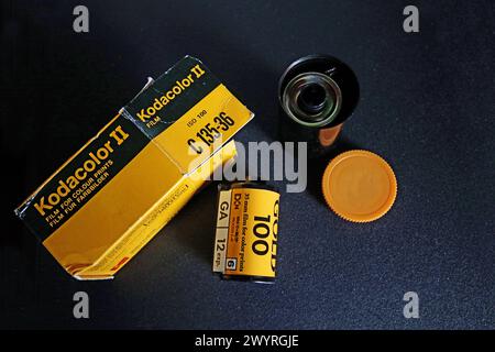 Fotografia analogica vintage: Nastro in rotolo di pellicola a colori Kodak da 35 mm con contenitore e confezione di carta, sfondo scuro Foto Stock
