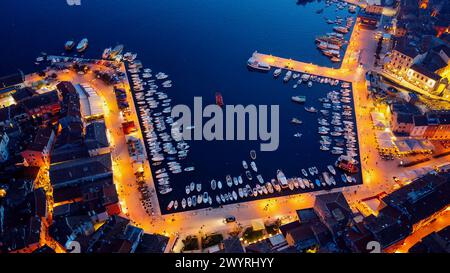 Vista panoramica della città serale al tramonto. Fotografia aerea. Luci sulle lanterne al crepuscolo. Le navi sono nella baia. Tetti piastrellati di case in t Foto Stock