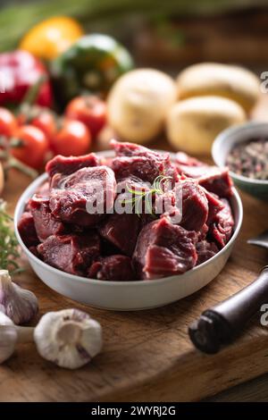 Pezzi di manzo tritato in un recipiente con verdure, pronti per il gulasch. Foto Stock