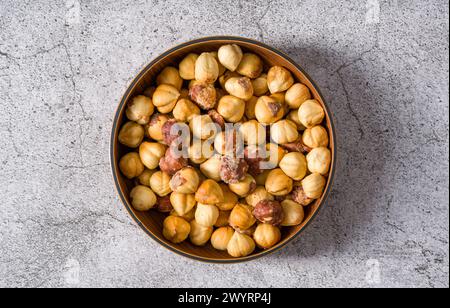 Nocciole salate arrostite in un recipiente di legno su un tavolo di pietra Foto Stock