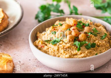 Hummus, purea di ceci con coriandolo in una ciotola su sfondo chiaro Foto Stock