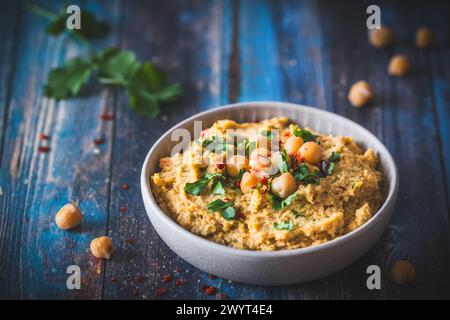 Hummus, purea di ceci con coriandolo in una ciotola su sfondo chiaro Foto Stock