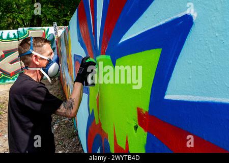 Graffity Artist Creating Graffity Artist Creating Jet un altro pezzo di arte urbana su parti dell'ex muro di Berlino, al confine con l'ex Germania Est o. Foto Stock