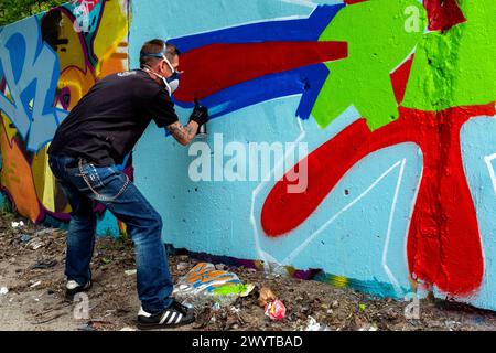 Graffity Artist Creating Graffity Artist Creating Jet un altro pezzo di arte urbana su parti dell'ex muro di Berlino, al confine con l'ex Germania Est o. Foto Stock