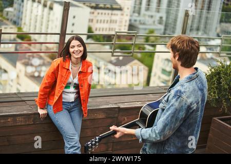 Una donna tiene in mano una chitarra mentre si trova accanto a un uomo in una scena armonica e musicale Foto Stock