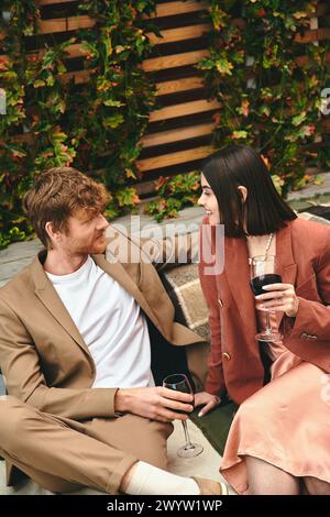 Un uomo e una donna trovano conforto mentre si siedono insieme su una panchina di legno, godendosi la compagnia degli altri e la tranquillità dell'ambiente circostante Foto Stock