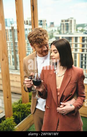 Un uomo e una donna stanno con grazia, lei tiene un bicchiere di vino. Trasudano raffinatezza e intimità nel loro momento condiviso Foto Stock