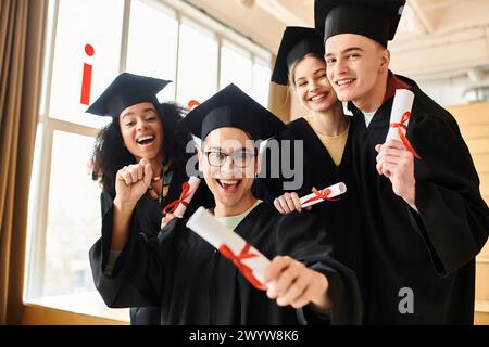 Un gruppo eterogeneo di studenti in camici e coppe di laurea che posa gioiosamente per un'immagine per commemorare il loro successo accademico. Foto Stock