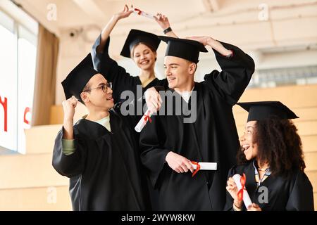 Un gruppo di giovani studenti di varie origini etniche che festeggiano con i loro abiti e cappellini di laurea. Foto Stock