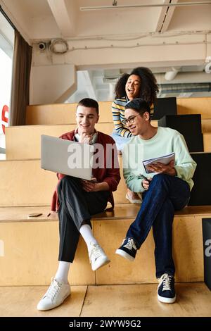 Un gruppo multiculturale di studenti seduti a chiacchierare su una scala all'interno di un'università o di una scuola superiore Foto Stock