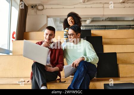 Gruppo multiculturale di studenti, tra cui una ragazza afroamericana, seduti insieme in cima a una scala interna Foto Stock
