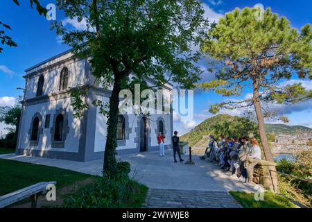 Grupo de Tourist atendiendo la explicaciones de un guia en la Casa del Faro de la Isla Santa Clara, en su interior se encuentra la obra Hondalea, 2020, de la escultora Cristina Iglesias, excavada en el interior de la Casa del Faro vaciada, la obra incorpora la geología y ecología de la Costa vasca y la bravura de las aguas del Mar Cantábrico, Símbolo de la defensa de causas ecológicas y de la Conservación del Medio ambiente, Donostia, San Sebastian, Paesi Baschi, Spagna, Europa. Foto Stock