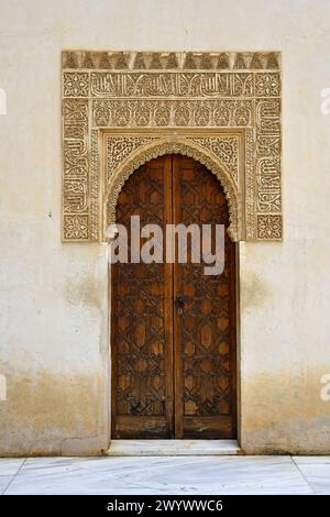 Elaborati intonaci in stile moresco e doppia porta ad arco in legno all'interno dei Palazzi Nasridi, Palazzo dell'Alhambra, Granada, Spagna Foto Stock