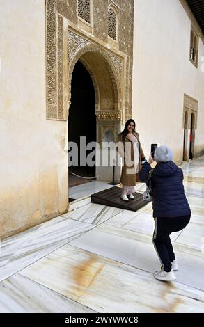 Il turista fotografa un amico con un elaborato arco in stile moresco all'interno dei Palazzi Nasridi, Palazzo dell'Alhambra, Granada, Spagna Foto Stock