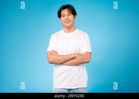 Allegro ragazzo con le braccia incrociate, sfondo blu Foto Stock