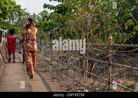 Visitatori, commercianti e immigrati birmani illegali camminano su filo spinato sul lato thailandese del confine tra Thailandia e Myanmar a Mae Sot, Thailandia. Foto Stock