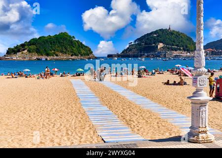 Bañistas en la Playa de Ondarreta, detrás la Isla Santa Clara y el Monte Urgull, Donostia, San Sebastian, Ciudad cosmopolita de 187,000 habitantes, destaca por su gastronomía, playas urbanas y edificios inspirrados en la arquitectura parisina, Gipuzkoa, Paesi Baschi, Spagna, Europa. Foto Stock