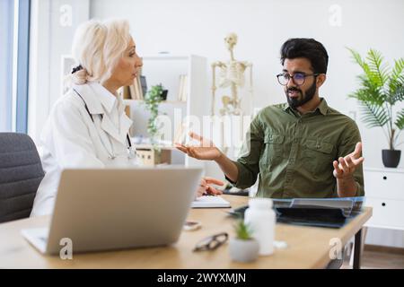 Medico anziano che fornisce consigli utilizzando il notebook per scrivere la prescrizione. Foto Stock