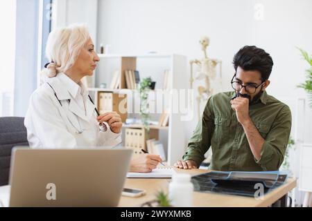 Medico di medicina generale che comunica con una giovane paziente tossiera. Foto Stock