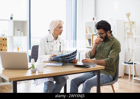 Donna dai capelli grigi con camice da laboratorio che regge la scansione RM. Foto Stock