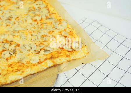 Una vista dettagliata di una pizza appena sfornata condita con funghi a fette, con crosta dorata e condimenti salati. Foto Stock