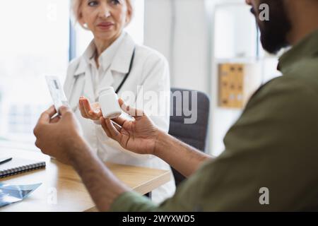 Uomo barbuto che tiene una bottiglia e un blister di pillole e ascolta i consigli del medico Foto Stock