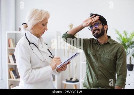 Medico anziano che fornisce raccomandazioni e scrive prescrizione. Foto Stock