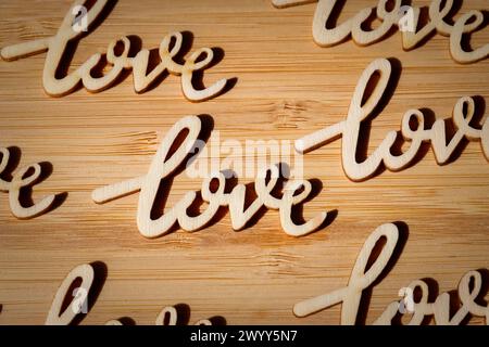 parola amore nel legno ripetuto più volte su tavola di legno, con ombra Foto Stock