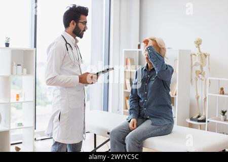 Medico con barba adulta che fornisce consigli e utilizza il tablet. Foto Stock