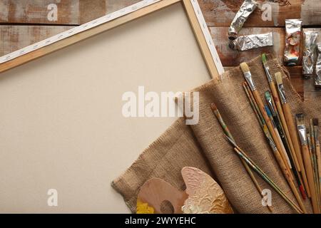 Tessuto in burlap naturale e diversi prodotti per la pittura su tavolo in legno, vista dall'alto Foto Stock