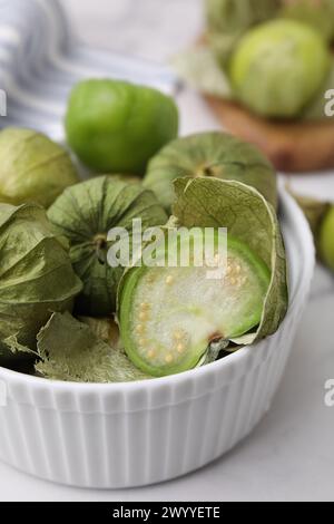 Tomatillo verde fresco con buccia nel recipiente sul tavolo leggero, primo piano Foto Stock