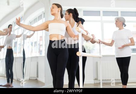 Giovane ballerina che pratica mosse al balletto barre durante le prove di gruppo Foto Stock