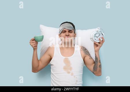 Giovane stressato con macchie di caffè sulla sua camicia senza maniche su sfondo blu Foto Stock