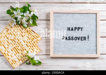 Felice Pesach flatlay. Pane matzo ebraico e fiori su sfondo di legno bianco. Biglietto d'auguri per le festività. Copia spazio. Foto Stock