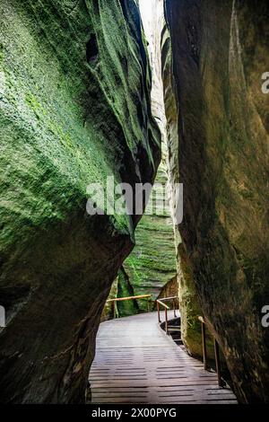 Stretta passerella in legno tra due grandi rocce Foto Stock